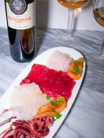 sashimi on long white plate with glass of orange wine