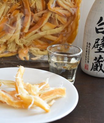 Japanese dried squid on plate with bottle of junmai sake