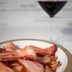 bacon strips on plate with glass of red wine