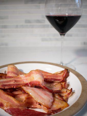bacon strips on plate with glass of red wine