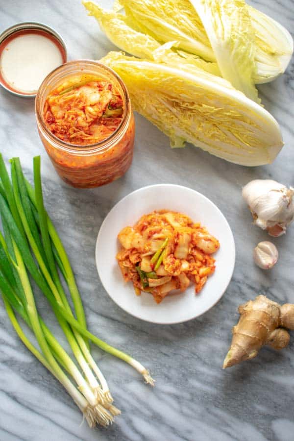 Kimchi on white plate and in bottle with vegetables
