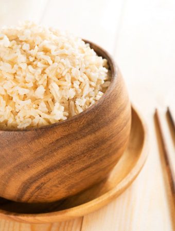 the best rice in a brown wooden bowl with chopsticks