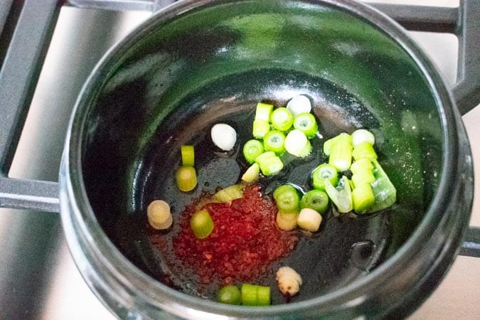 Green onion and chili flakes in black pot for Vegan Korean Soft Tofu Soup