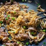 beef ramen noodle stir fry in a black nonstick pan with black chopsticks