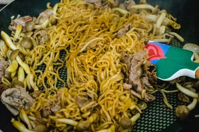 ramen noodles with beef and mushrooms in pan with spatula