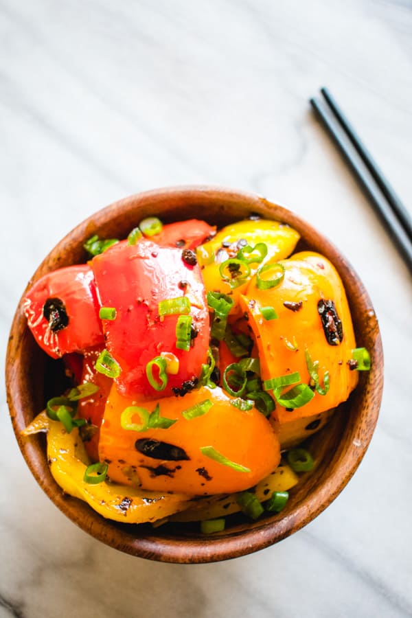 Healthy bell peppers with vegan black bean sauce in wood bowl with black chopsticks on the side. 