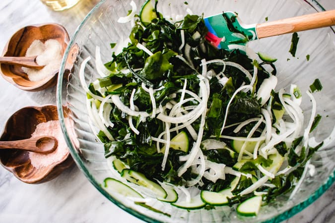 Korean seaweed salad tossed in a glass bowl with a spatula.