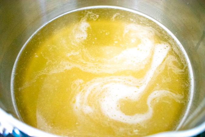 Close up of chicken stock in a stainless steel pot
