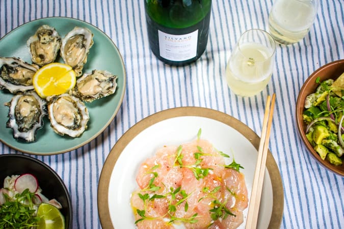 Plates of oysters, hamachi carpaccio, and ceviche with 2 glasses of cartizze prosecco
