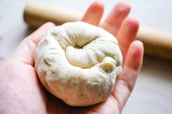 Coil of green onion puff pastry in the palm of a hand