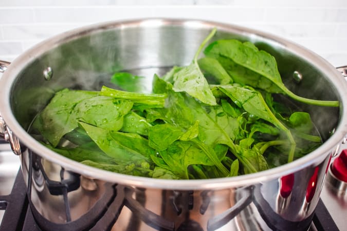 Spinach in a hot stock pot of water for Korean chap chae noodles.