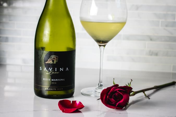 Savina Lane Petit Manseng wine with a red rose