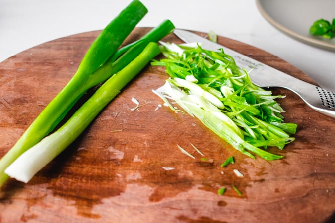 julienned scallions on a brown cutting board