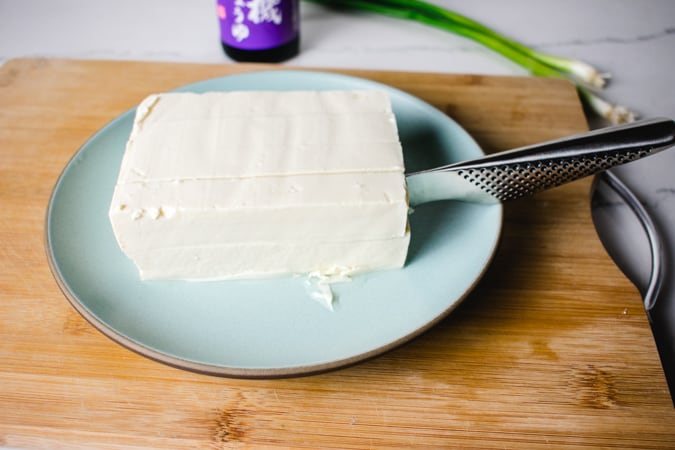 knife cutting into a block of silken tofu