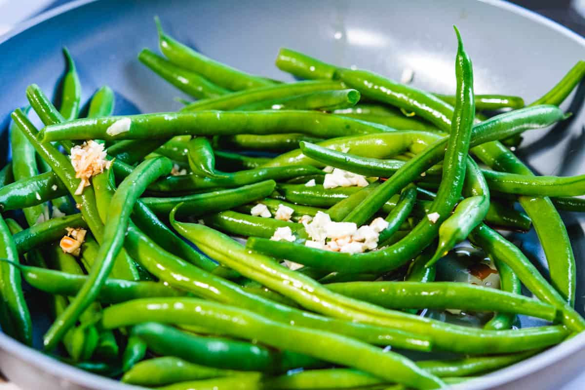 raw green beans and minced garlic in a pan