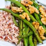close up of roasted green beans, walnuts, and brown rice in a white bowl