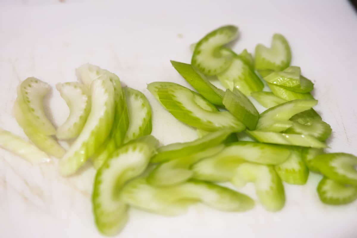 celery sliced on the bias on a white cutting board