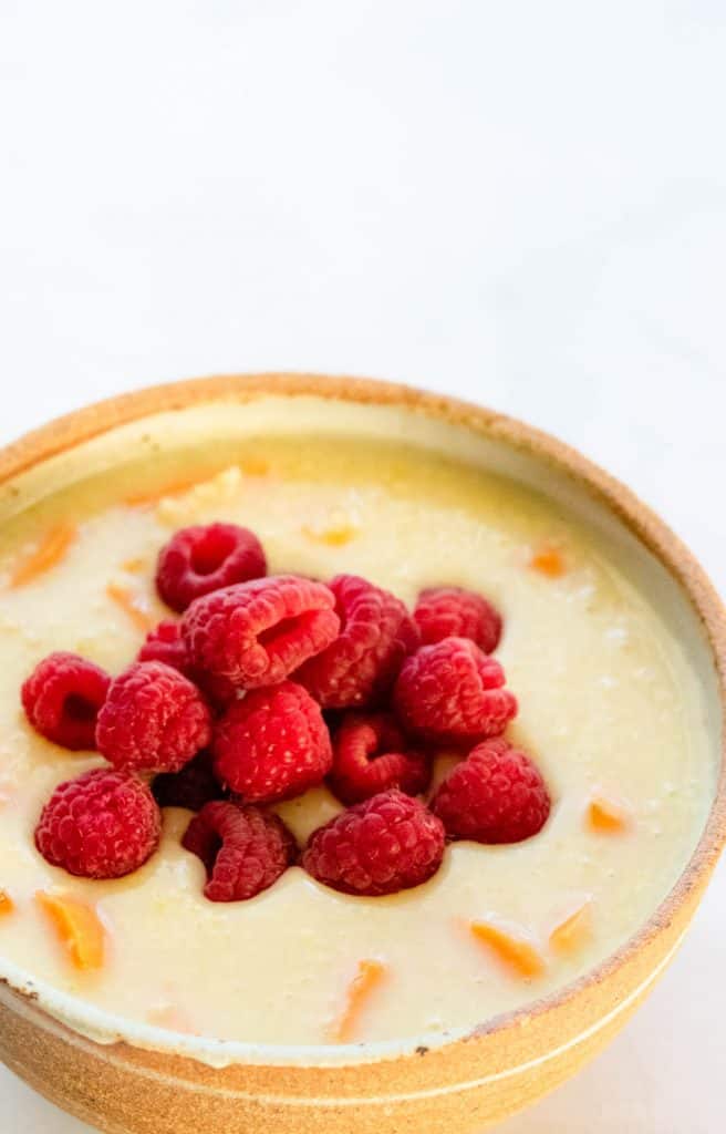 close up shot of vegan millet porridge with raspberries and sweet potatoes in a bowl