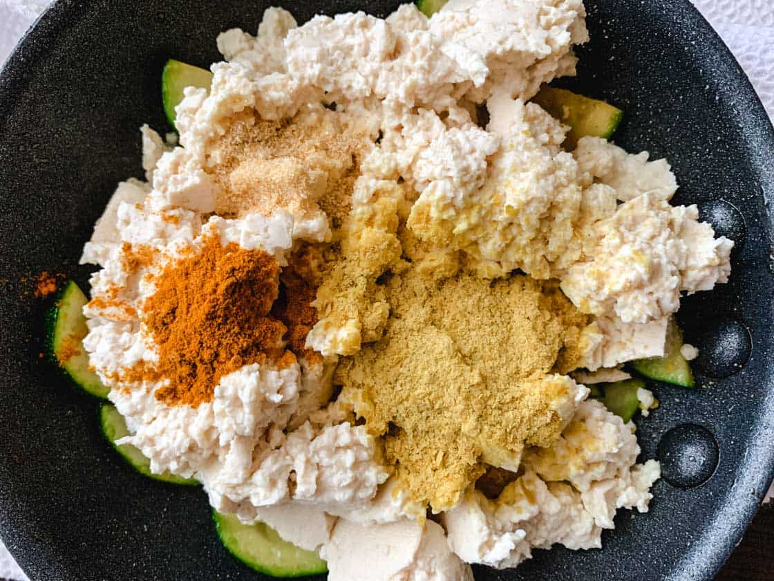 mashed tofu with spices in a black pan